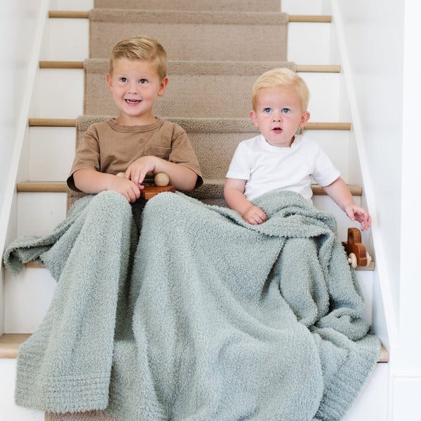 Two boys smiling, wrapped in their Sage BAMBONI® TODDLER BLANKETS - Saranoni