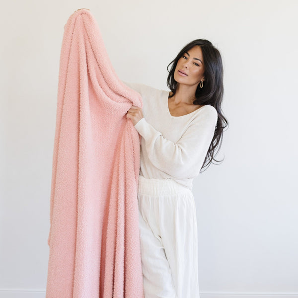 Woman holding out beautiful, soft and stretchy, Peach BAMBONI® XL BLANKETS - Saranoni