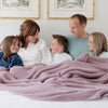 Entire family snuggling together in bed in beautiful Woodrose BAMBONI XL BLANKETS - Saranoni