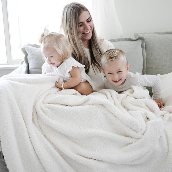 Mom, little boy, and little girl all laughing and smiling, snuggled in their Ivory BAMBONI XL BLANKETS - Saranoni