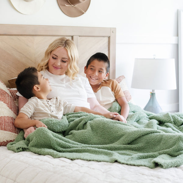 Happy family snuggling in bed with Olive Green BAMBONI XL BLANKETS - Saranoni