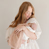 Mother holding her baby girl wrapped in a beautiful and soft bamboo muslin quilt. 