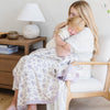 Mom and daughter snuggling together with a beautiful purple floral bamboo muslin quilt. 