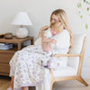 Mother and daughter happily cuddling together while wrapped in a soft, lightweight purple floral bamboo muslin quilt. 