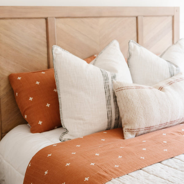 Elegant details of an orange, swiss cross bamboo muslin quilt and pillowcase.