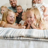 Family enjoying time together accompanied by a blue striped muslin bamboo quilt.