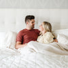 Husband and wife snuggling in bed with a luxurious bamboo rayon muslin bedding quilt, offering a soft, breathable layer for a restful night's sleep.