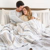 Husband and wife laying in bed with a Beautifully crafted bamboo rayon muslin quilt for bedding, combining softness and breathability for cozy nights.