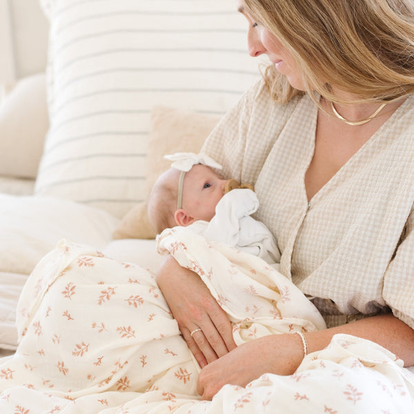 Mother snuggling daughter with a dainty floral printed swaddle.