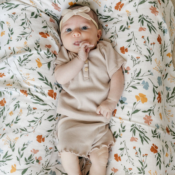 Baby girl laying on a soft and breathable bamboo muslin swaddle, perfect for wrapping your baby in gentle comfort.