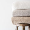 Stack of high-quality boucle blankets in an ivory, cream and tan colors. - Saranoni