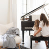 Durable and stylish Boucle blanket laid out on the couch next to a mother and daughter practicing piano - Saranoni