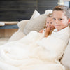 Kids snuggling up together in a luxurious ivory Boucle blanket in the living room - Saranoni