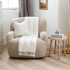 Cozy beige armchair with white xl throw blanket and pillow next to wooden side table- Saranoni