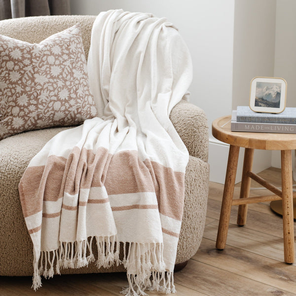 Cozy living room with a cream chair adorned by a cream and tan striped xl throw blanket, adding warmth to the neutral decor - Saranoni