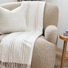 Close-up of white xl throw blanket with beige stripes draped over beige armchair- Saranoni