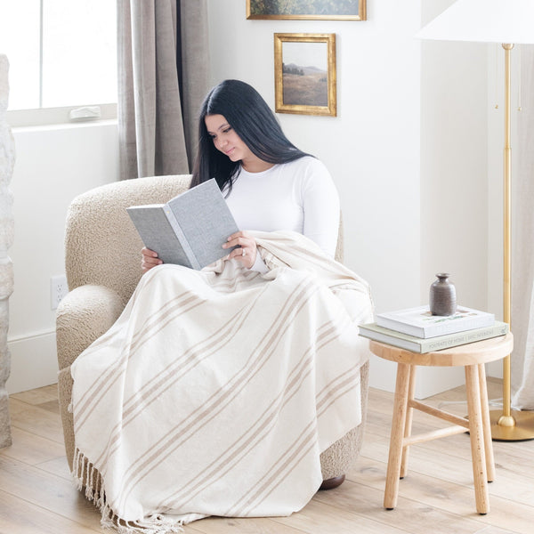 Person curled up with a book and a plush xl chenille fringe blanket - Saranoni