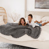 A brother and sister on a soft, gray Saranoni chunky knit throw blanket. The large knit Saranoni blanket, is made from 100% poly microfiber and drapes beautifully. This luxury throw blanket is both trendy and durable, making it the perfect addition to any space. Ideal for home decor enthusiasts and those seeking a cuddly, soft blanket, this chunky knit blanket combines style and comfort. Keywords: chunky knit throw, soft blanket, knit blanket, large knit blanket, luxury throw blanket.