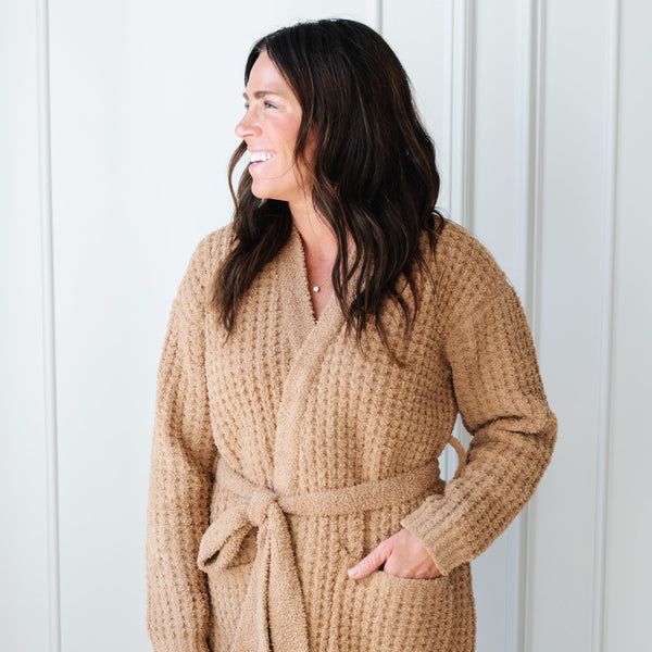 Woman happily snuggled in her tan Waffle Knit robe.