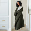 Woman wrapped up in a cozy, luxurious, green waffle knit blanket. 