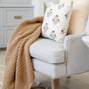 Tan waffle knit blanket draped over living room chair. 