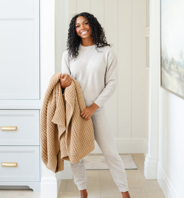 Woman holding a tan XL waffle knit blanket.