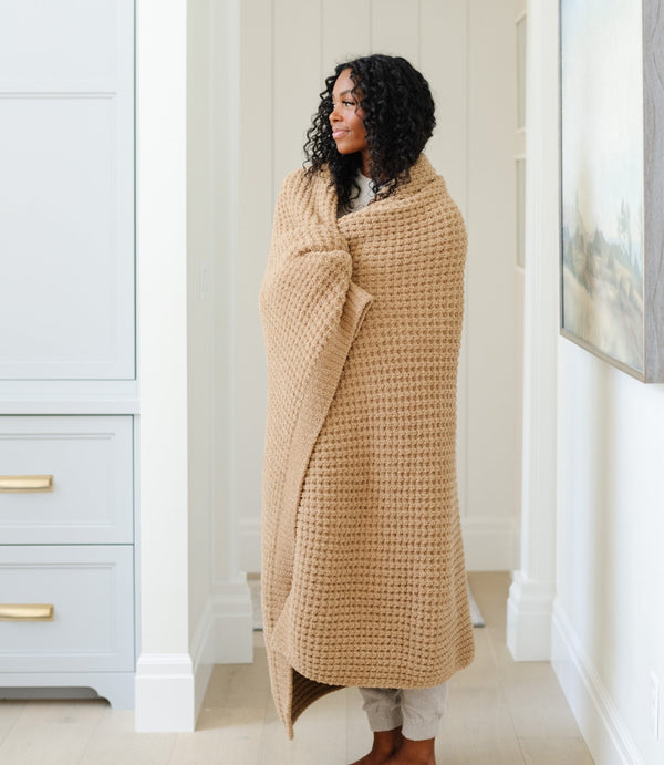 Woman wrapped up in a cozy, tan XL waffle knit blanket. 