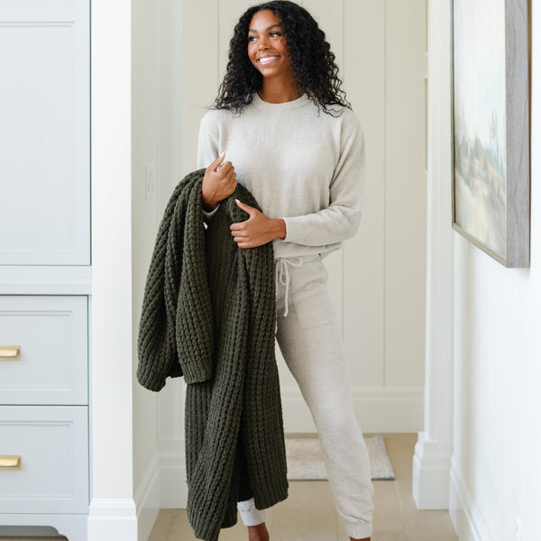 Woman holding a waffle knit XL throw blanket in deep green