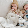 Two little boys sitting up with extra soft and stretchy Swiss Cross DOUBLE-LAYER BAMBONI MINI BLANKETS - Saranoni