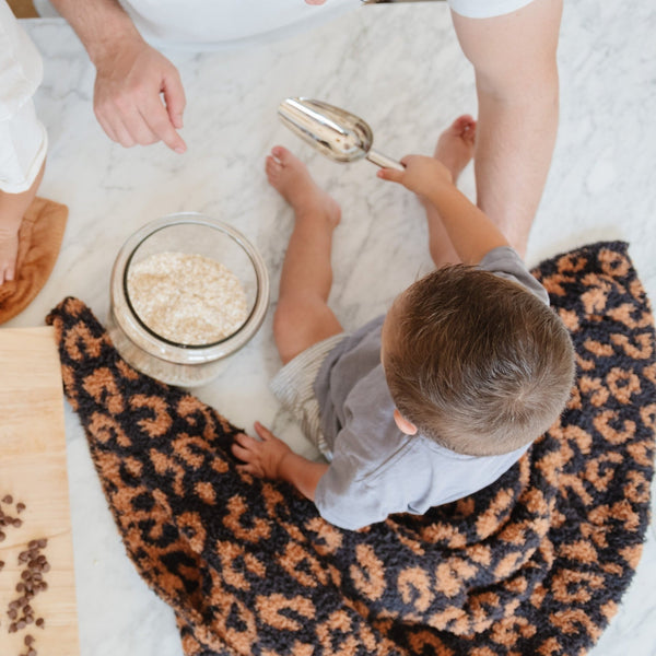 Family making cookies in the kitchen with little boy sitting on Classic Leopard DOUBLE-LAYER BAMBONI RECEIVING BLANKETS - Saranoni