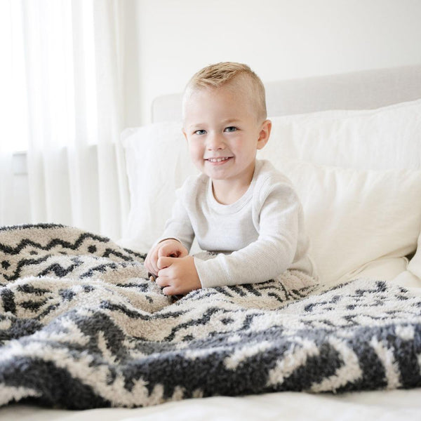 Little boy sitting in bed with  super soft and stretchy Mudcloth DOUBLE-LAYER BAMBONI RECEIVING BLANKETS - Saranoni