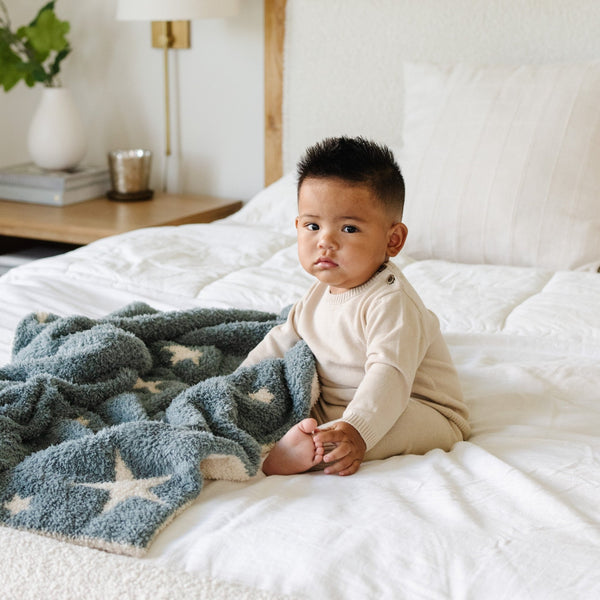 Young, adorable boy sitting with extra stretchy and soft Nightfall (Blue and White Stars) DOUBLE-LAYER BAMBONI® RECEIVING BLANKETS - Saranoni