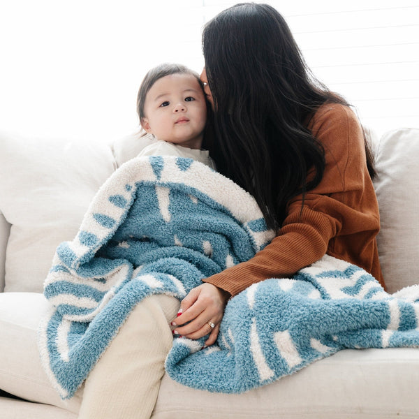 Mom and little girl snuggling on the couch with Blue Triangle DOUBLE-LAYER BAMBONI RECEIVING BLANKETS - Saranoni