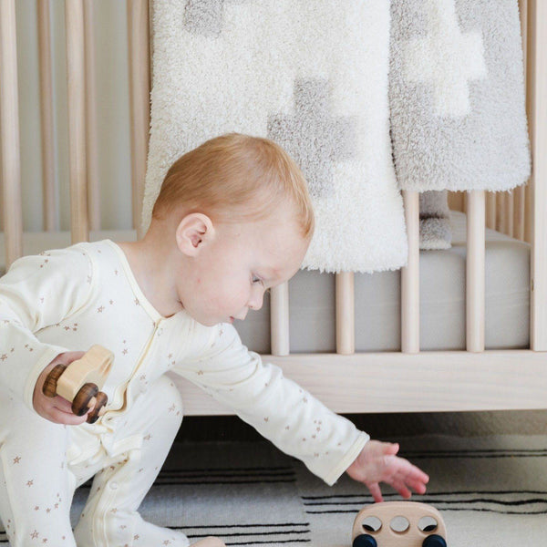 Little boy playing with wooden toys in beautiful room with Swiss Cross DOUBLE-LAYER BAMBONI RECEIVING BLANKETS - Saranoni