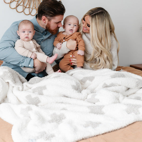 Beautiful family of four snuggled together in soft and stretchy Swiss Cross DOUBLE-LAYER BAMBONI THROW BLANKETS - Saranoni