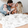 Beautiful family of four snuggled together in soft and stretchy Swiss Cross DOUBLE-LAYER BAMBONI THROW BLANKETS - Saranoni