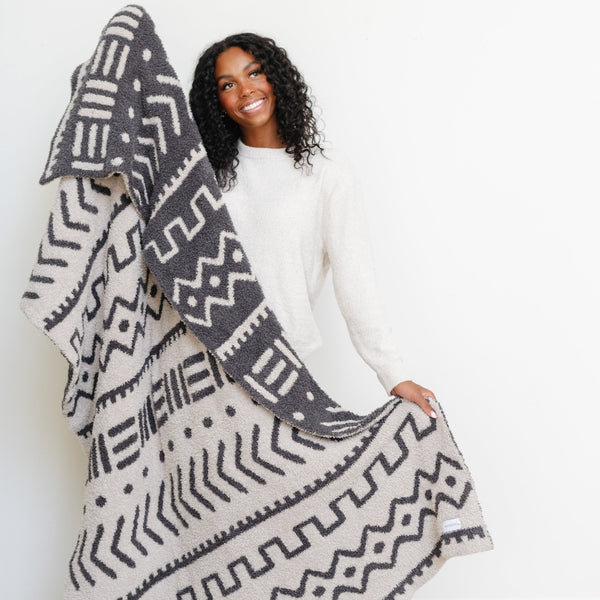 Woman showing off both sides to a beautiful Mudcloth DOUBLE-LAYER BAMBONI® THROW BLANKETS - Saranoni