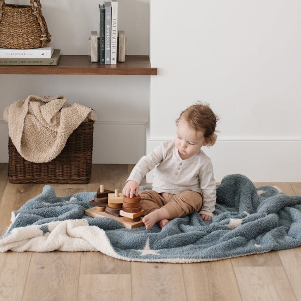 Little boy playing with wooden toys, sitting on super soft and comfy Blue + White Stars Nightfall DOUBLE-LAYER BAMBONI TODDLER BLANKETS - Saranoni