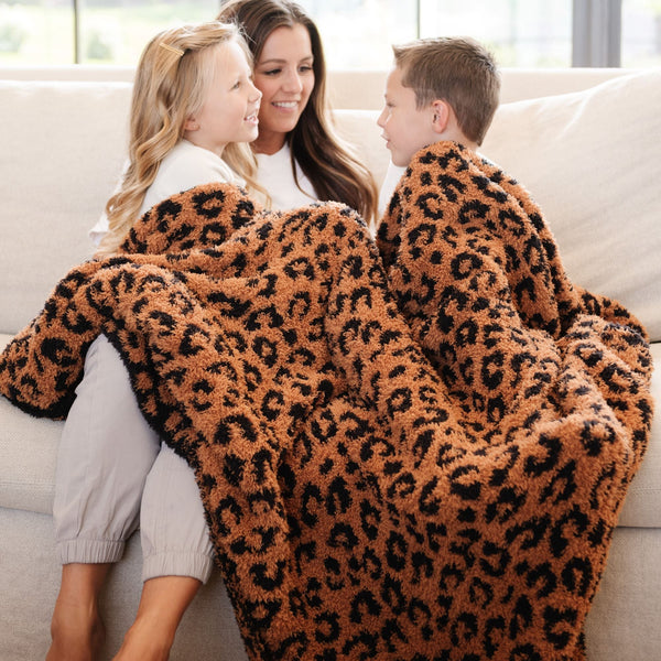 Family snuggled together on the couch in beautifully soft Classic Leopard DOUBLE-LAYER BAMBONI TODDLER BLANKETS - Saranoni