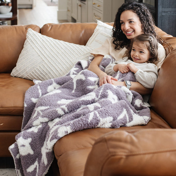 Mom and little girl snugglin on couch with super stretchy soft Purple Pansy DOUBLE-LAYER BAMBONI TODDLER BLANKETS - Saranoni