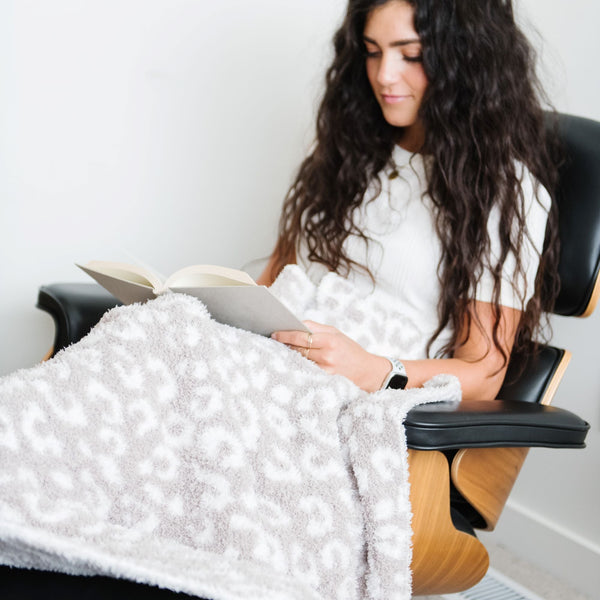 Girl reading a book while sitting with beautiful and warm Gray Leopard DOUBLE-LAYER BAMBONI XL BLANKETS - Saranoni