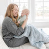 Mom and newborn snuggling on couch with DREAM RECEIVING BLANKETS - Saranoni