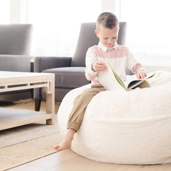 Child sitting on a Saranoni Bean Bag, enjoying a cozy read in a bedroom setting.