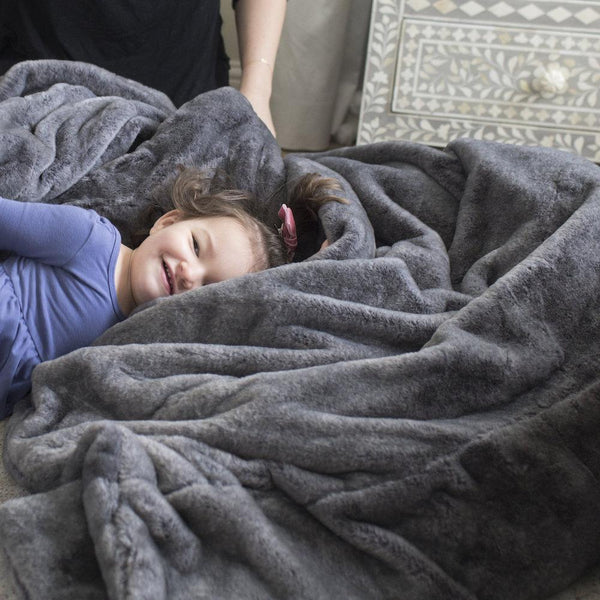 Child enjoying the cozy feel of a Saranoni blanket in a bedroom.