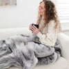 GRAND FAUX FUR SLEEPING BAGS - Teen snuggled in a gray mink sleeping bag, showing the medium gray fur-like color.