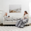 GRAND FAUX FUR SLEEPING BAGS - Adults comfortably wrapped in a large gray mink sleeping bag, enjoying the plush texture.