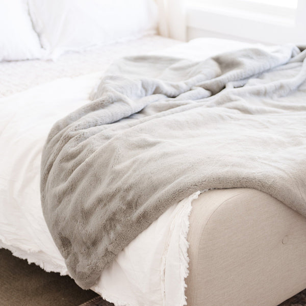 XL Grand Faux Fur blanket draped over a bed.