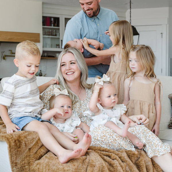 A family cozying up together under a luxurious Saranoni blanket.