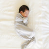 A baby boy lays on a soft, white Saranoni Heirloom Cotton Knit Receiving Blanket with the name "Oliver" embroidered on it. The luxury 100% cotton blanket features classic cable knit detailing, a wide border, making it a timeless keepsake. The cozy, elevated blanket, is perfect for special occasions like baby showers or newborn photoshoots. Ideal for searches related to personalized baby blankets, soft cotton receiving blankets, or heirloom-quality baby gifts.