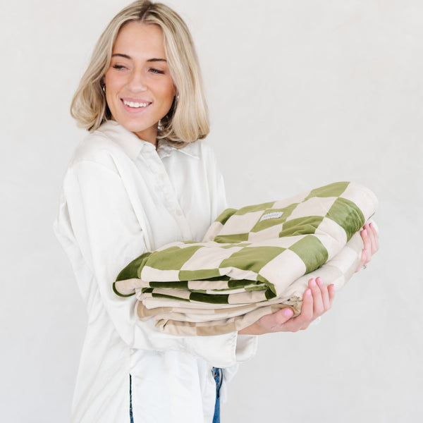 Girl holding two checkered MINKY STRETCH RECEIVING BLANKETS - Saranoni